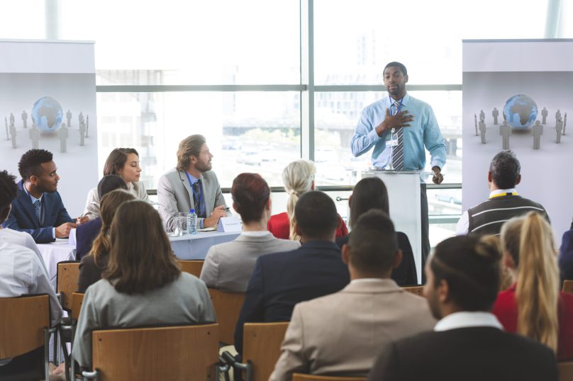 Front view of African American businessman speaker speaking in a business seminar in modern office building