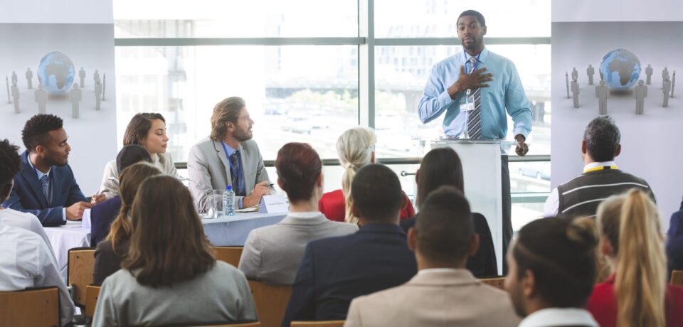 Front view of African American businessman speaker speaking in a business seminar in modern office building