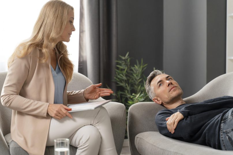 Mid shot man laying couch therapy cabinet near woman counselor