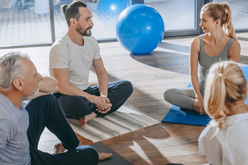 Senior people with instructor exercising together on yoga mats