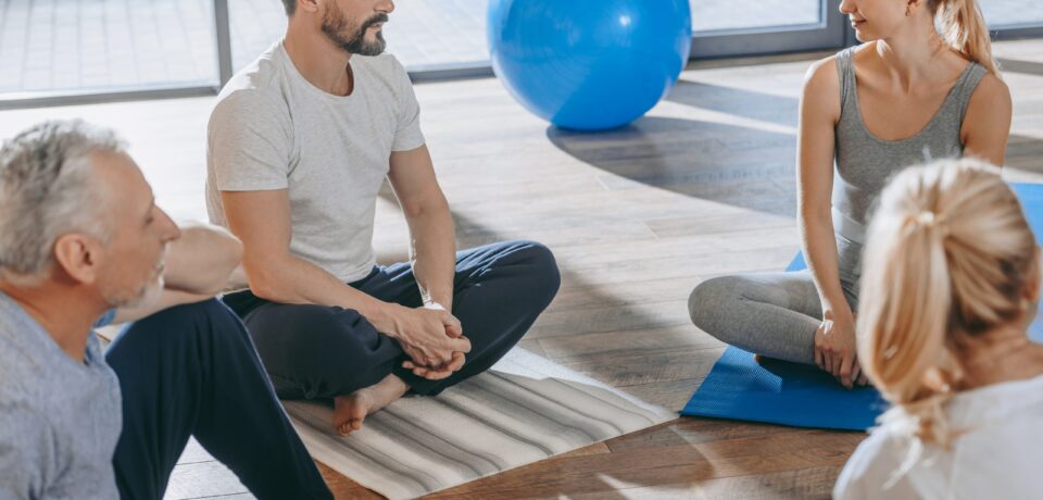 Senior people with instructor exercising together on yoga mats